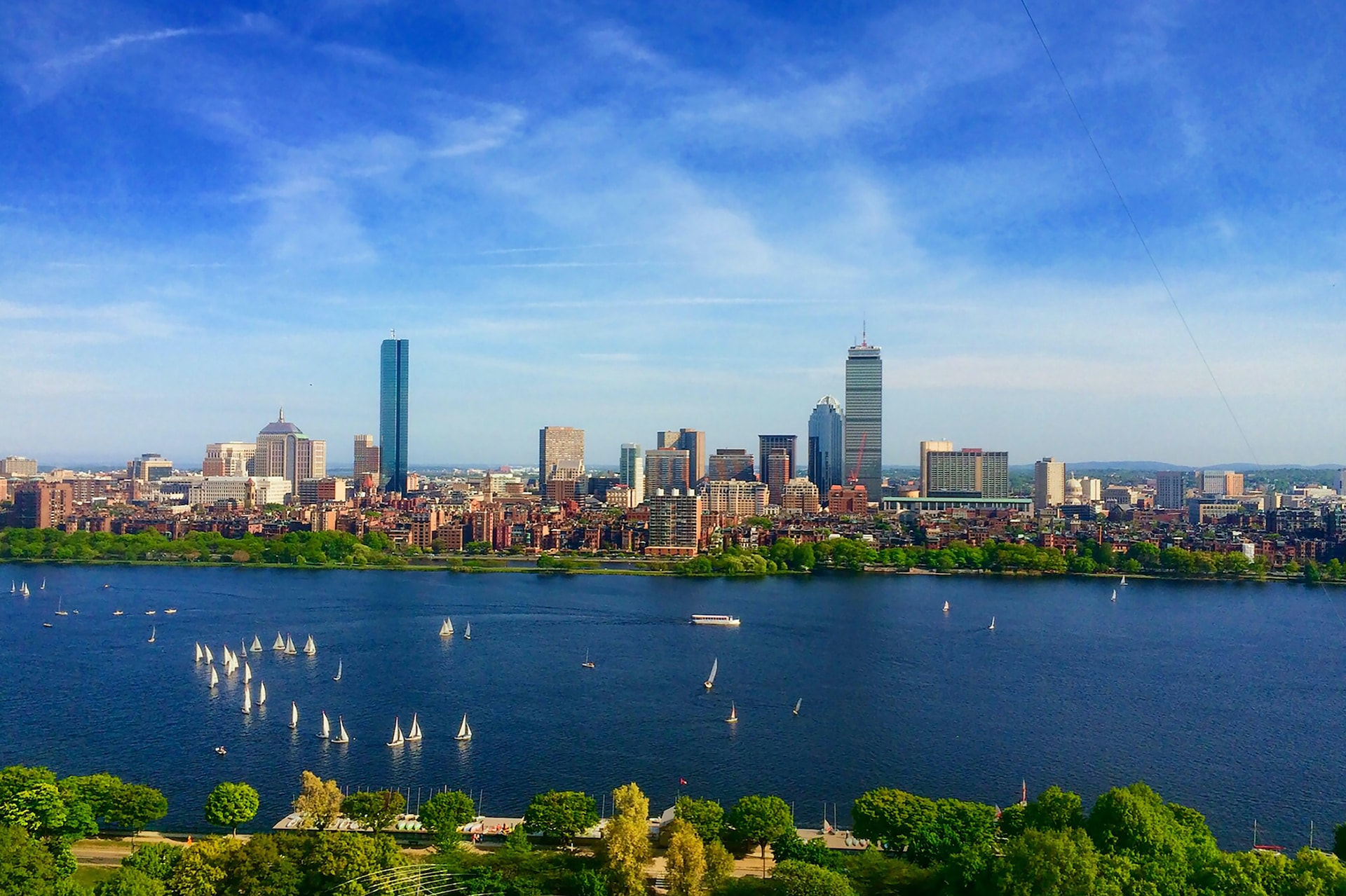 A view of downtown Boston in the state of Massachusetts showcasing numerous towering buildings and the great Charles River in the foreground.