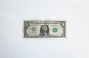 A US Dollar bill lying flat on a white surface, prominently displaying the face of former US President George Washington.