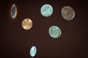 Several coins of US currency flying through the air.