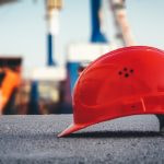 A worker’s hard hat helmet sitting on the ground of a construction site.