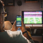 An image of someone watching TV whilst viewing a betting app
