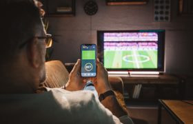 An image of someone watching TV whilst viewing a betting app