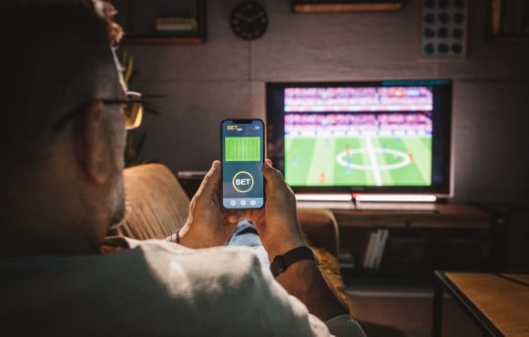 An image of someone watching TV whilst viewing a betting app