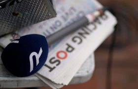 A Racing TV microphone sits on a Racing Post newspaper.