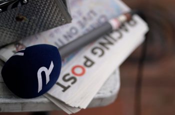 A Racing TV microphone sits on a Racing Post newspaper.