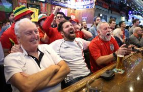 Football fans excitedly watching a game in a pub.