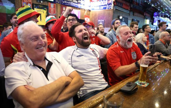 Football fans excitedly watching a game in a pub.