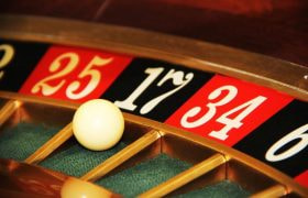 An image showing a roulette wheel with a ball at a casino.