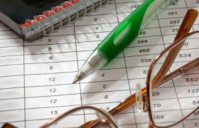 A Notebook, Pen, Glasses and a Piece of Paper with a Table
