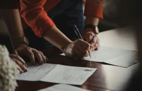 Two People at a Desk Signing Documents