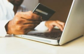 Person Using a Laptop and Holding a Debit Card