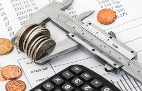 Mätinstrument som mäter mynt ovanpå ett papper som innehåller siffror