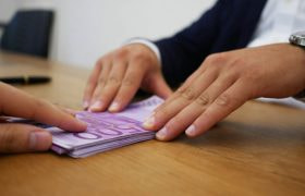 A Person Giving Someone a Pile of Banknotes