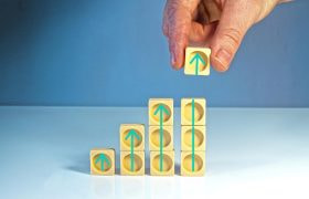 Hand som illustrerar ökad omsättning med hjälp av klossar