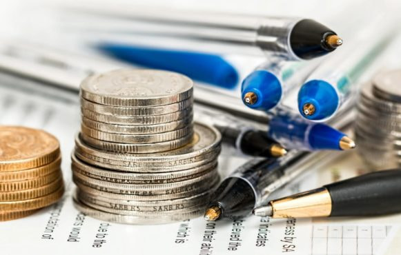 Högar med mynt, pennor och formulär