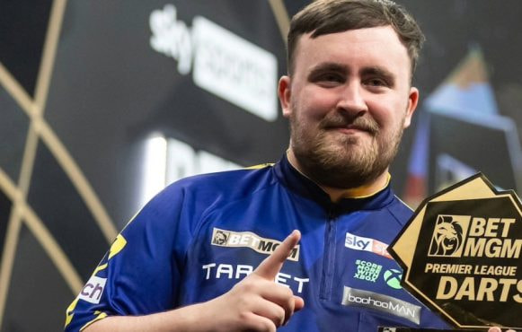 Luke Littler holds aloft one of his Premier League trophies.