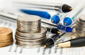 Pengar och pennor i högar på ett papper