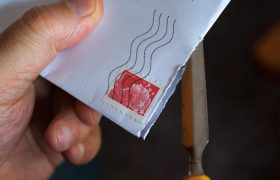 En hand håller i ett brev med ett frimärke på