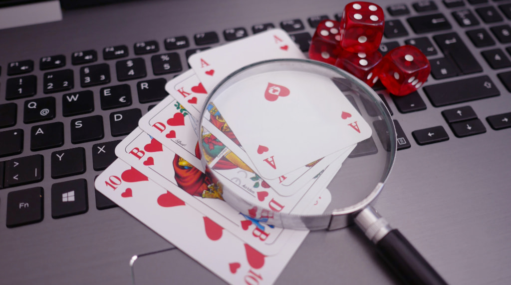 Playing cards, dice, and a magnifying glass, placed upon a laptop to symbolise an analysis of online casino trends.