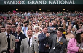 Crowds Watch and Cheer Horses During the 2024 Randox Grand National at Aintree Racecourse.