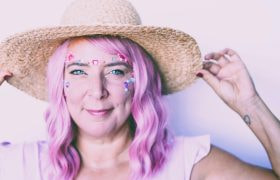 En kvinna med rosa hår, hatt, och strass som signalerar girl power