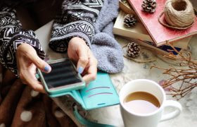 Kvinna sitter med mobil i handen och spelar