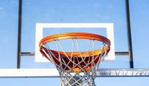 Close-up of an orange basketball hoop and net against a clear blue sky