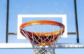 Close-up of an orange basketball hoop and net against a clear blue sky