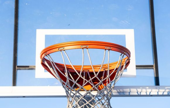 Close-up of an orange basketball hoop and net against a clear blue sky