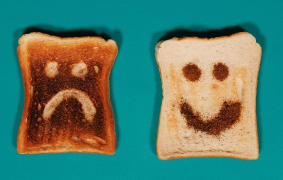Twee geroosterde boterhammen met een verdrietig en vrolijk gezichtje