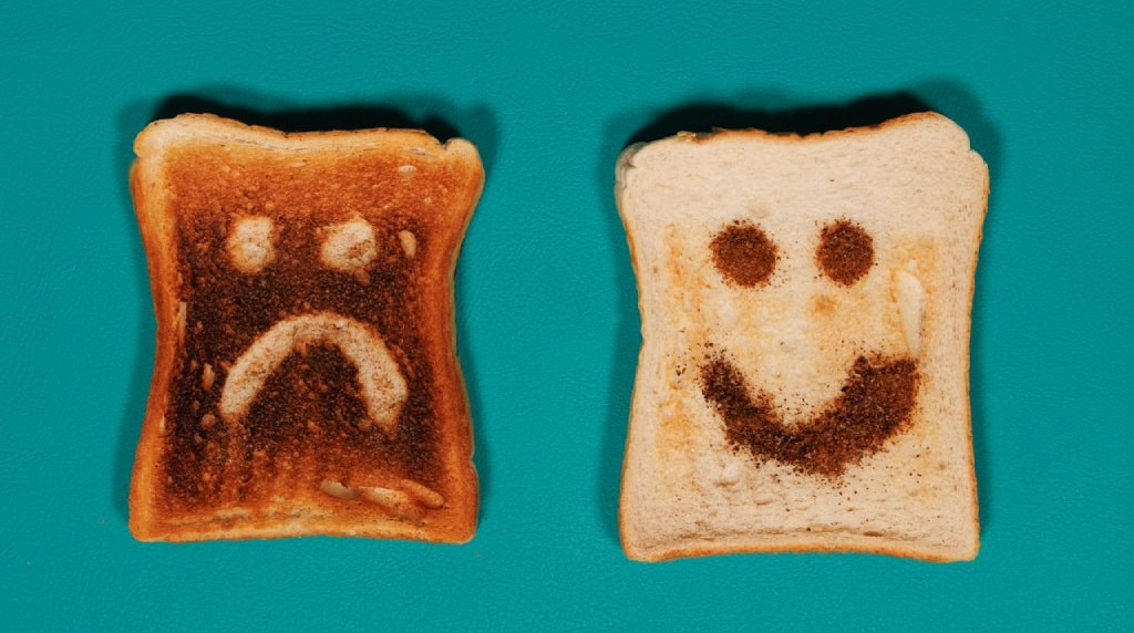 Twee geroosterde boterhammen met een verdrietig en vrolijk gezichtje