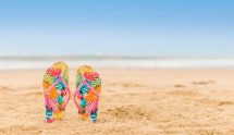 Kleurrijke slippers die steken uit het zand op het strand