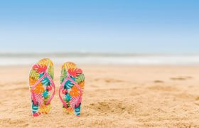 Kleurrijke slippers die steken uit het zand op het strand