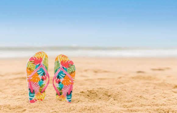 Kleurrijke slippers die steken uit het zand op het strand