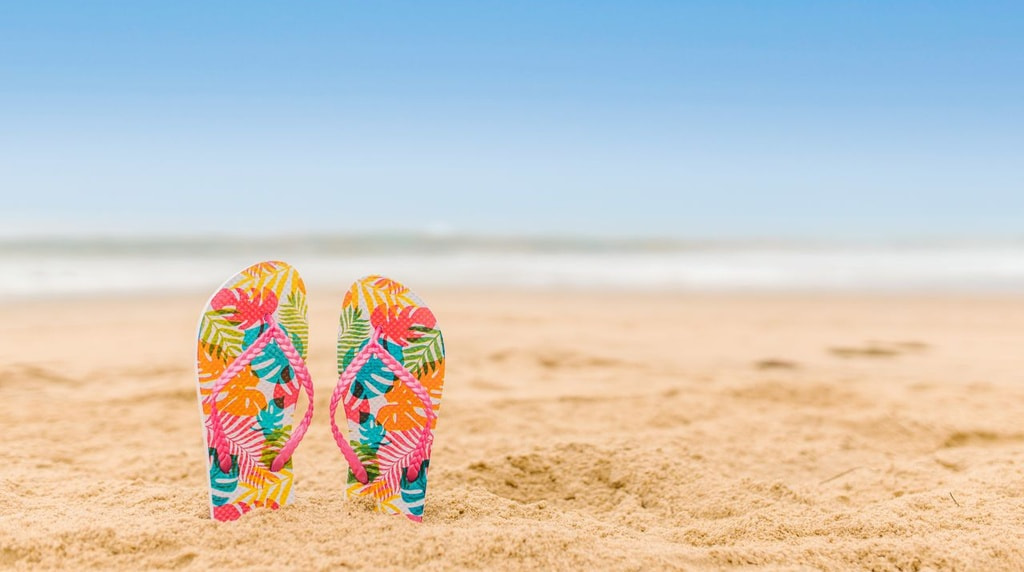 Kleurrijke slippers die steken uit het zand op het strand