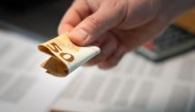 Mannenhand die een opgevouwen briefje van 50 euro geeft