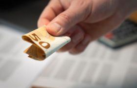 Mannenhand die een opgevouwen briefje van 50 euro geeft