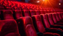 Empty red movie theater seats under projector lights