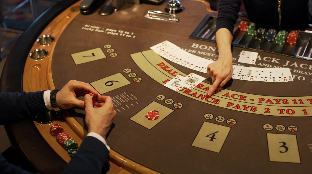 Person i sort sidder ved blackjackbord