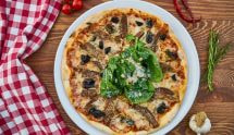 Pizza farcita con verdure, acciughe, olive, formaggio e insalata