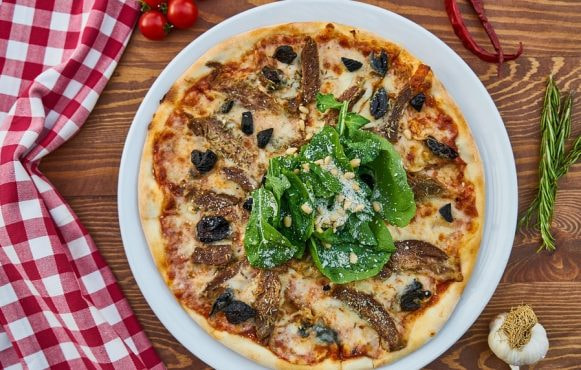 Pizza farcita con verdure, acciughe, olive, formaggio e insalata
