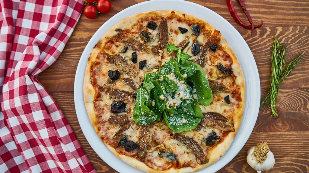 Pizza farcita con verdure, acciughe, olive, formaggio e insalata