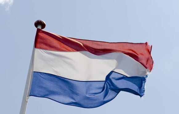 Det hollandske flag der vejrer i luften med en blå himmel som baggrund.