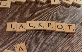 Tessere di Scrabble che formano la parola “JACKPOT” su un tavolo di legno