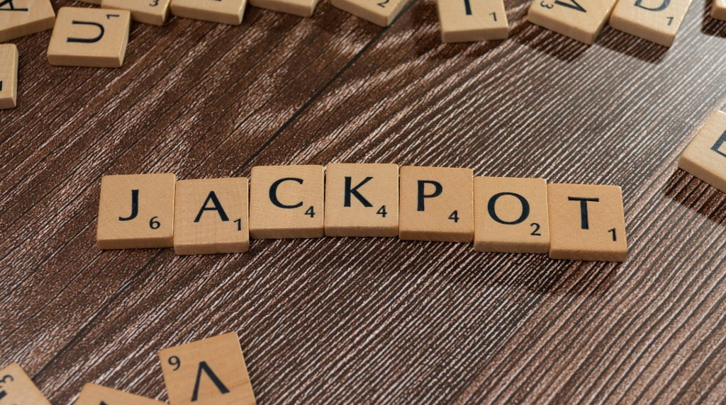 Tessere di Scrabble che formano la parola “JACKPOT” su un tavolo di legno