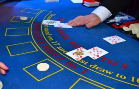Tavolo da blackjack con carte, fiches e mazziere in azione