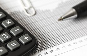 Calcolatrice e penna su documento con grafico e dati numerici.