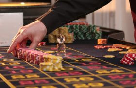 Una mano sistema fiches colorate su un tavolo da roulette.