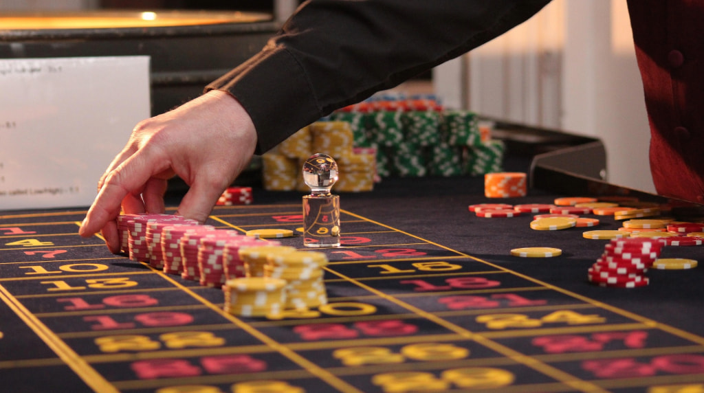Una mano sistema fiches colorate su un tavolo da roulette.