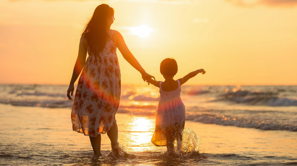 Donna e bambina al tramonto sulla spiaggia.